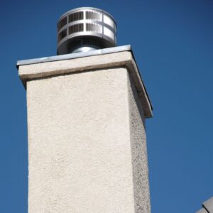 a white stucco chimney with a metal chimney cap