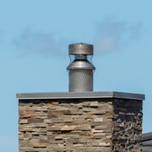 a masonry chimney with a metal chase cover and chimney cap