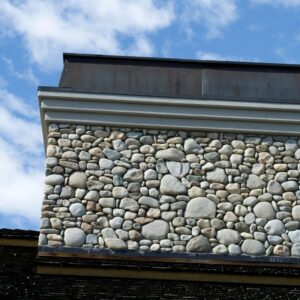 a gray stone chimney with a chimney cap