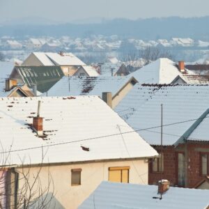 multiple rooftops with chimneys all covered in snow