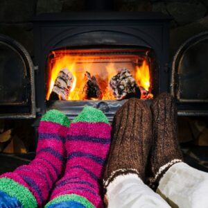 socked feet propped up by a burning wood stove