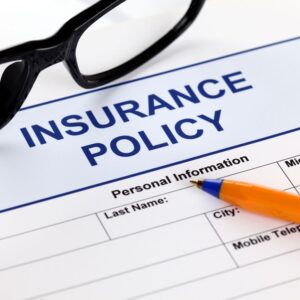 an insurance policy paper with a pen and glasses on top