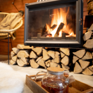 a wood fireplace insert surrounded by wood logs and a drink in front of it