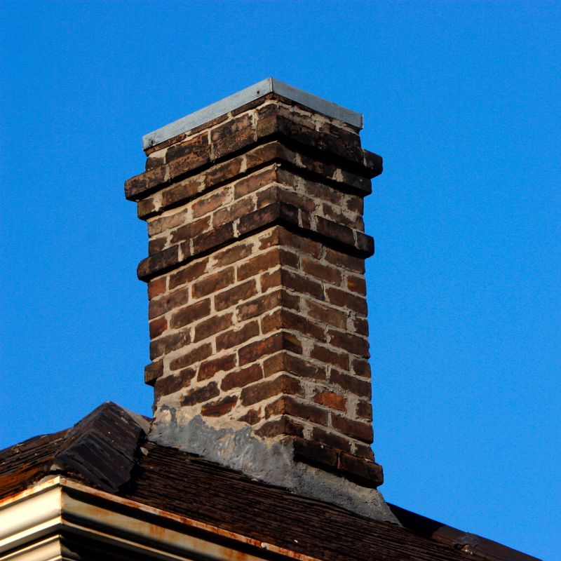 dark brick masonry chimney against a bright blue sky