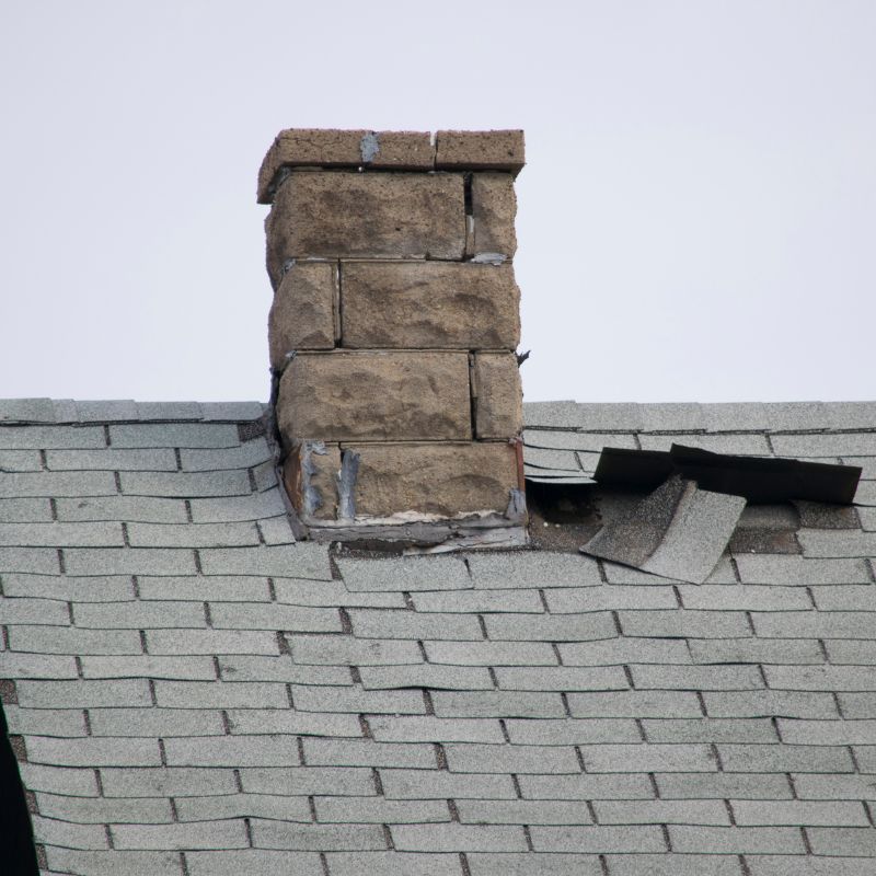 a broken down chimney next to a big hole in a roof